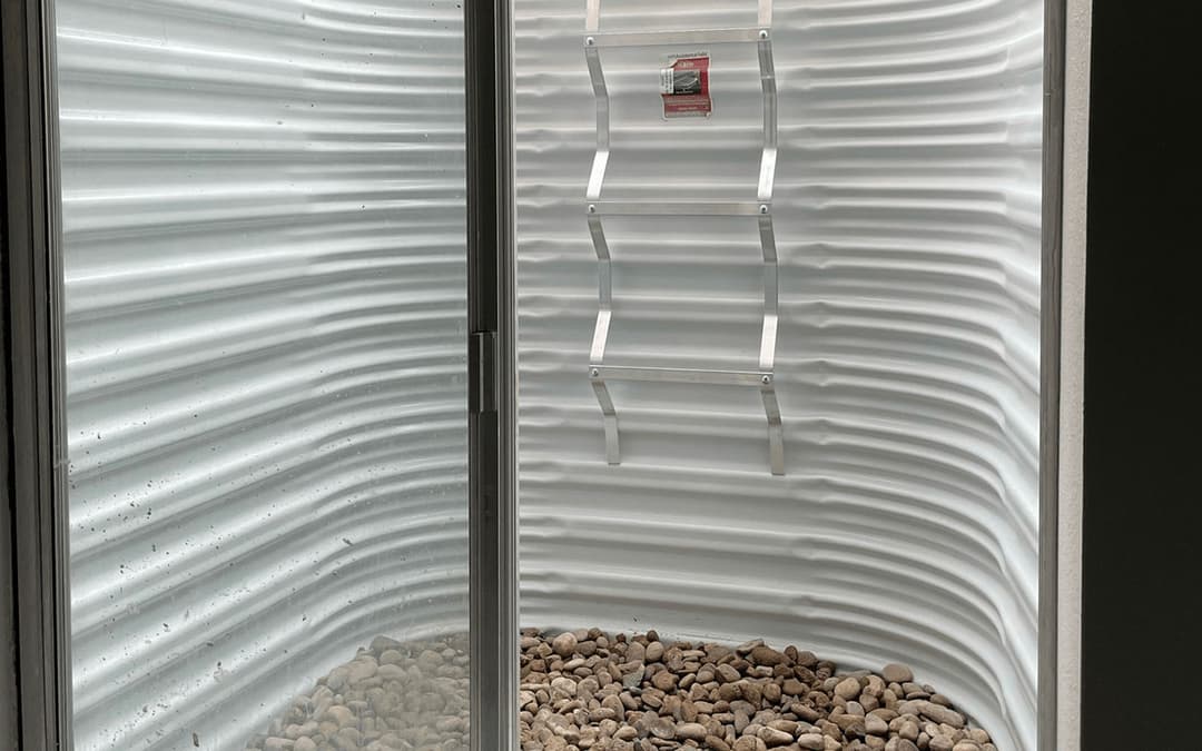 Interior view of a unique, curved wall design featuring a stone base and a metallic ladder.