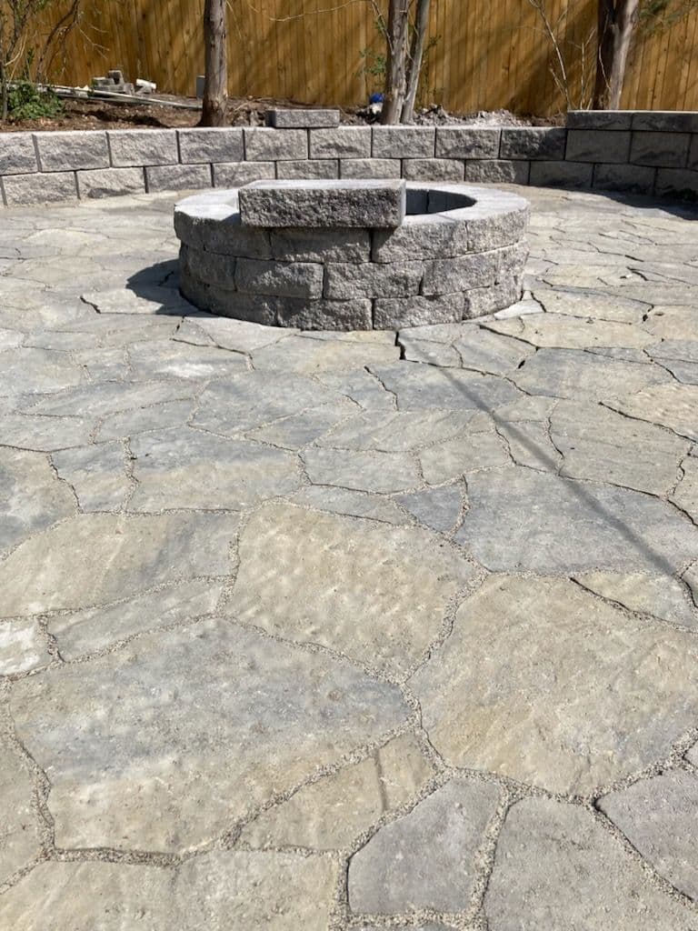 Patio area featuring a circular stone fire pit and irregular flagstone pavement.